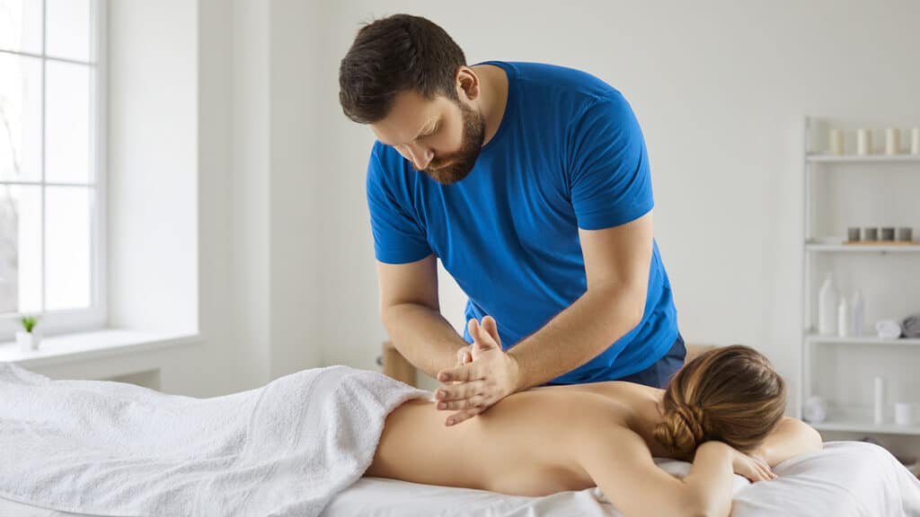Therapist performing flowing Swedish massage strokes on a client's back